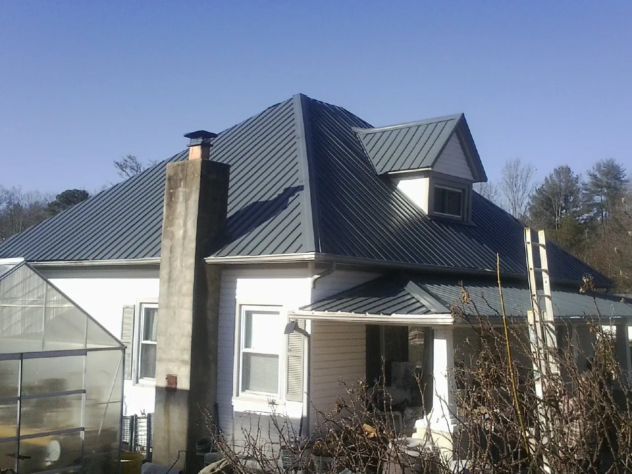 Dark blue standing seam metal roof on a white farmhouse with dormer — Slate & Tile Roof Repair by Roofing Brothers in Peabody