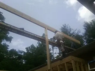 Carpenter setting a ridge beam over a new addition frame — Ice Dam Removal by Roofing Brothers in Peabody